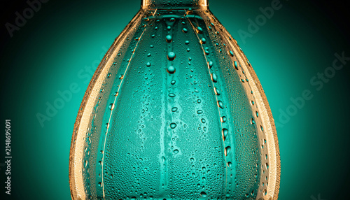 Close Up Teal Bottle With Water Droplets Under Dramatic Lighting.