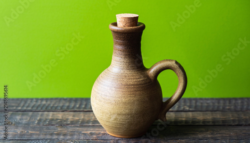 Rustic Ceramic Pitcher On Wooden Table Against Bright Green Backdrop.
