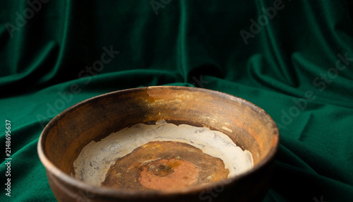Rusty Metal Pot Resting on Deep Green Velvet Background.