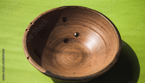 Ceramic Brown Bowl Resting on Green Fabric.
