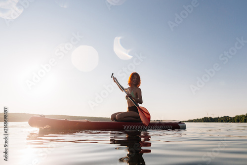 Woman enjoying stand up paddle boarding at sunset