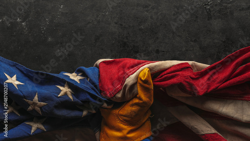 Hand in worn work glove holding the American flag. Symbolic of hardworking blue collar workers, USA manufacturing, pride in products Made in United States of America, or to celebrate US Labor Day.