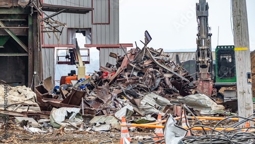 View of a demolition site with a large pile of scrap metal and heavy machinery in the USA.