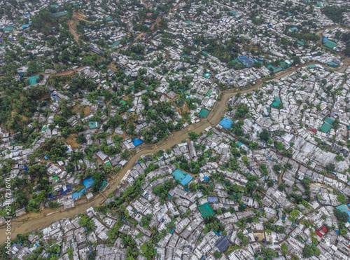 Cox's Bazar, Bangladesh - 17 July 2026: Aerial view of the densely populated refugee camp, featuring makeshift shelters with white and blue tarpaulin roofs, separated by a muddy stream.