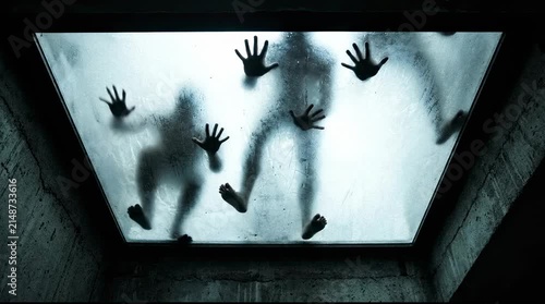 Silhouettes of people pressing hands against glass surface