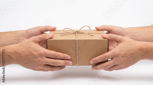 A brown gift box tied with twine being handed from one person to another. The gesture suggests exchange, delivery, or a surprise gift