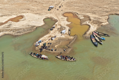 Aerial view of Jadukata River with local people boarding and disembarking from wooden boats along the sandy riverbanks in Sunamganj, Sylhet Division, Bangladesh.
