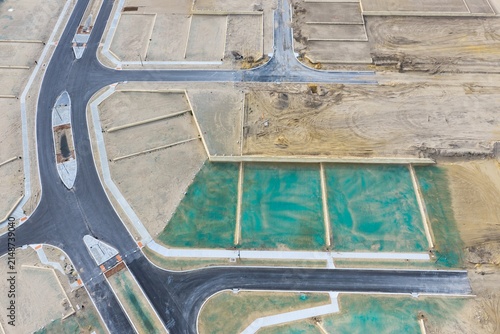 Aerial view of a new residential development site featuring newly paved roads and plots prepared for construction with green erosion control netting in Perth, Western Australia, Australia.