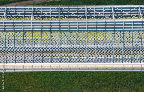 Aerial view of the metal truss bridge spanning the Vistula River with intricate lattice steelwork and green grassy banks in Tczew, Pomeranian Voivodeship, Poland.