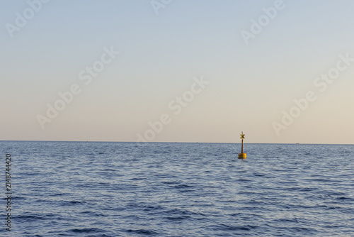 View of a yellow navigation buoy floating in the calm blue waters of the Ligurian Sea in Monterosso al Mare, Liguria, Italy.