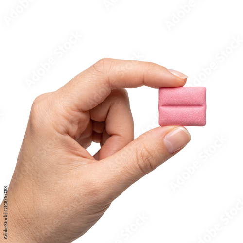 Hand holding pink chewing gum square isolated on black background