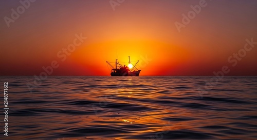Fishing Boat Sailing on Calm Ocean During Vibrant Sunset.