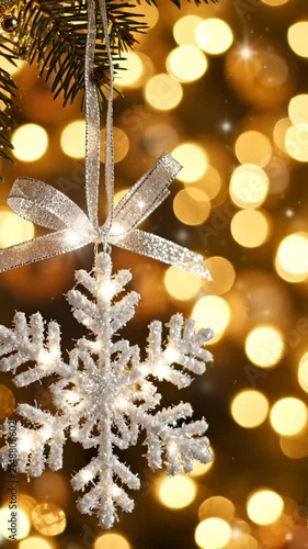 Glowing Snowflake Christmas Ornament Hanging on Pine Tree With Golden Bokeh Lights