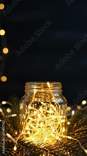 Glowing Christmas Fairy Lights Inside Glass Jar Surrounded by Pine Branches