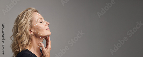 Mature Woman Touching Jawline with Cosmetic Treatment Markers