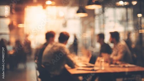 Blurred image of a group of people at a meeting in a warm toned environment