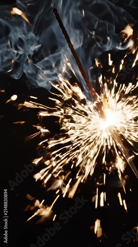 Bright Burning Sparkler Emitting Golden Sparks and Smoke Against a Dark Background