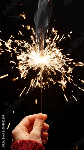Hand Holding a Burning Sparkler Against a Dark Background
