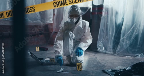 Crime scene investigator carefully holds and inspects a cartridge casing during forensic examination.