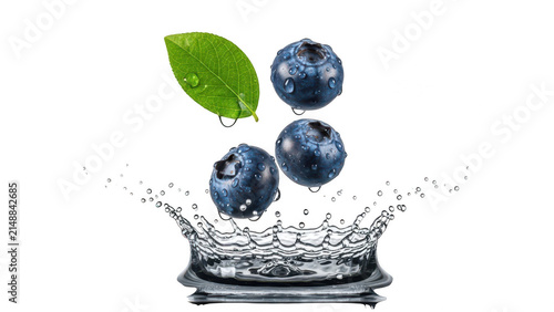 Fresh blueberries falling into water with splashes and green leaf