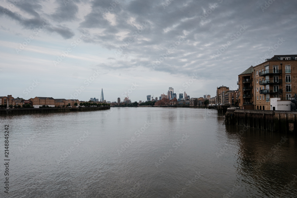 Obraz premium River thames flowing past london skyline under overcast sky