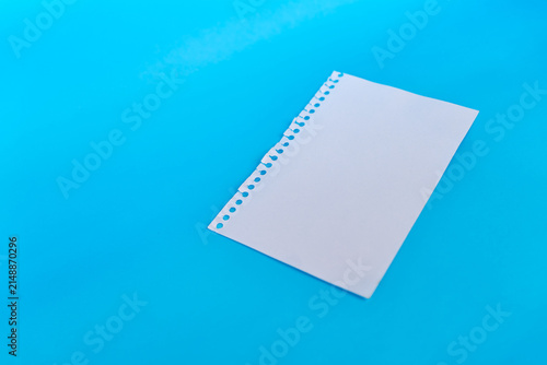 Fotografie Blank torn notebook paper sheet arranged diagonally on blue background