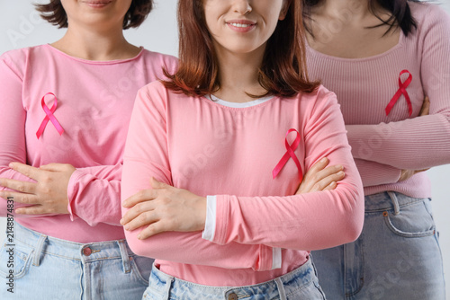 Women with pink ribbons on light background. Breast cancer awareness concept