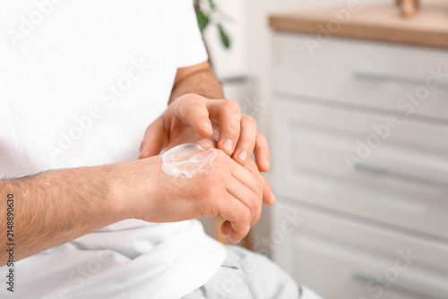 Young man applying cream on...