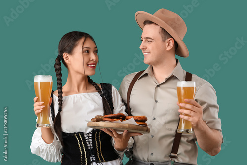 Young happy couple in traditional German clothes with glasses of beer and sna...