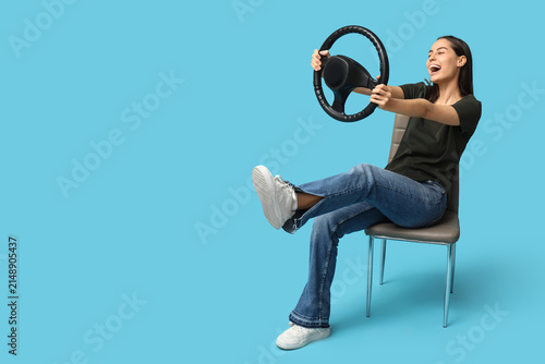 Foto Happy young woman with steering wheel on blue background