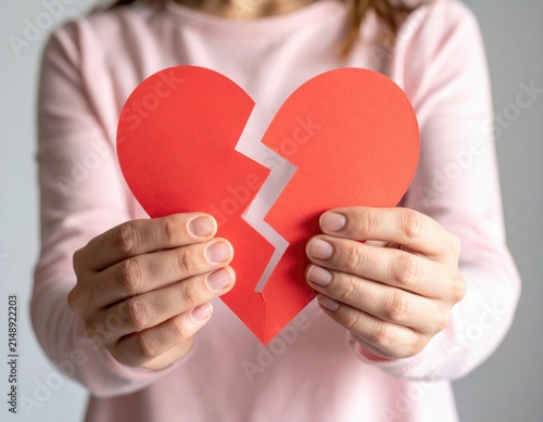 Hands holding broken heart shaped paper