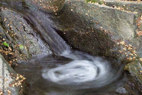 Water flowing into a small rock pool and swirling