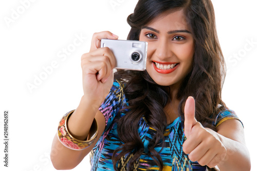 Young woman taking photograph with camera and showing thumbs up