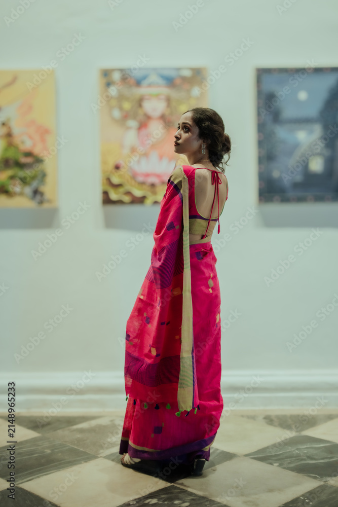 Fototapeta premium Elegant Portrait of an Indian Woman Wearing a Pink Saree Inside an Art Gallery