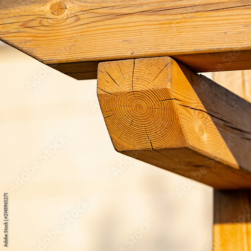 Natural wooden beam with distinct knot and grain detail under warm sunlight