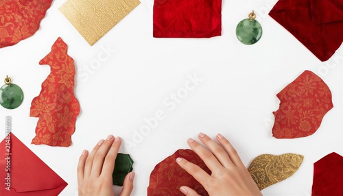 Hands making Chinese New Year paper craft on white background, DIY Lunar New Year red frame decoration.