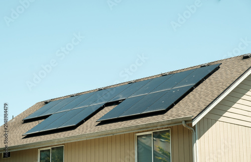фотографія Modern solar panels installed on the shingled roof of a suburban house