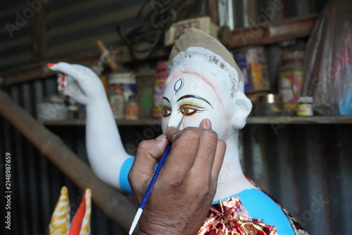 Artisan painting the eyes of a traditional clay goddess idol