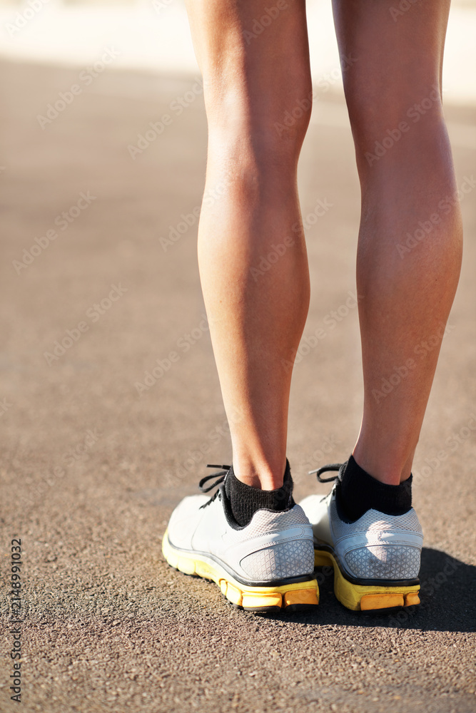 Obraz premium Legs, athlete and sneakers outdoor for fitness, exercise and endurance training for wellness. Feet, woman and runner on gravel road with cardio footwear, morning jog and sports workout for self care