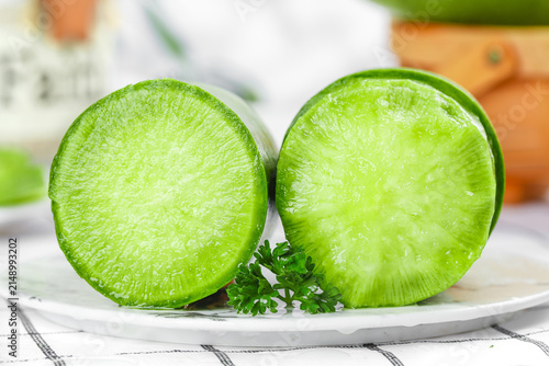Foto Fresh Green Radish Halves with Emerald Flesh and Parsley Garnish on White Plate