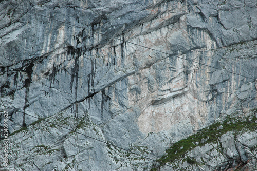 Photography A full frame shot capturing rugged grey limestone walls with wet patches and thi