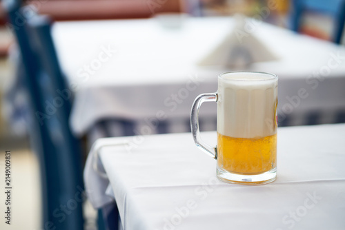 Cuadro en lienzo Close-up of a frosted glass mug filled with cold lager beer on restaurant table