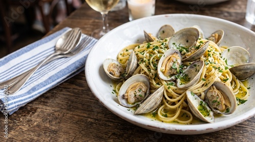 Linguine alle Vongole: Close-up of linguine pasta with fresh clams, garlic, olive oil, white wine, and parsley, in a white shallow bowl.