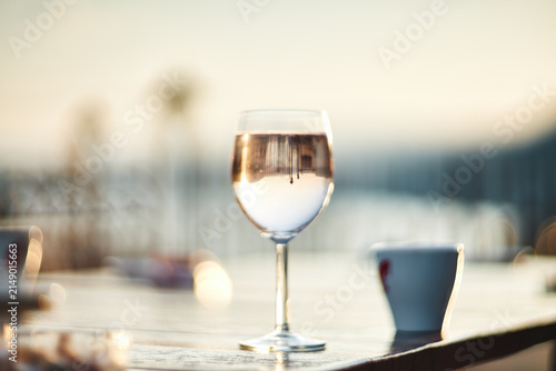 A close-up view of a glass of wine sitting on a wooden table outdoors
