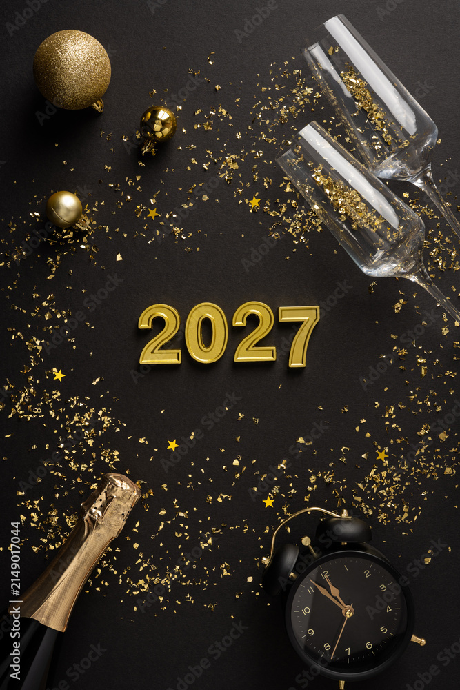 Obraz premium Happy New Year 2027 celebration with champagne, confetti, clock and golden decoration on vertical black backdrop