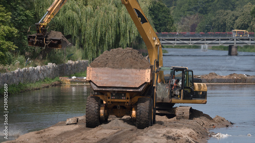 Foto EXCAVATOR AND ARTICULATED HAULER - Construction machines are working on the rive