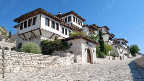 A picturesque cobblestone street leads to beautiful traditional houses with whitewashed walls and wooden accents, set against a clear blue sky, Ideal for travel, architecture, or cultural themes,