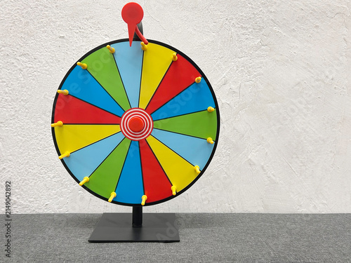 Colorful fortune wheel spinning with a pointer against a neutral textured background