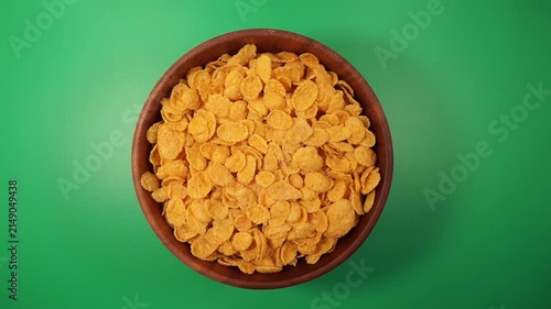 Cornflakes on a wooden bowl rotation on a green table