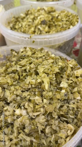 Salted cabbage in clear plastic tub, finely chopped Kroshevo on market counter, mixed with shredded carrot and dill, brine